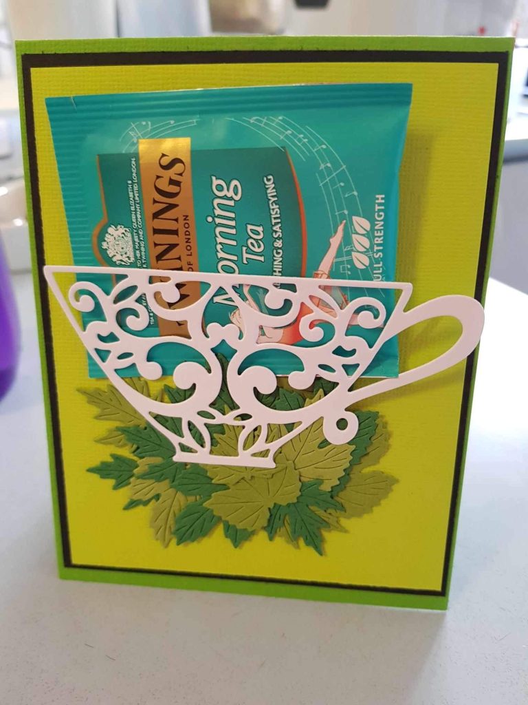 A hand made card of a tea cup with goodies in it.