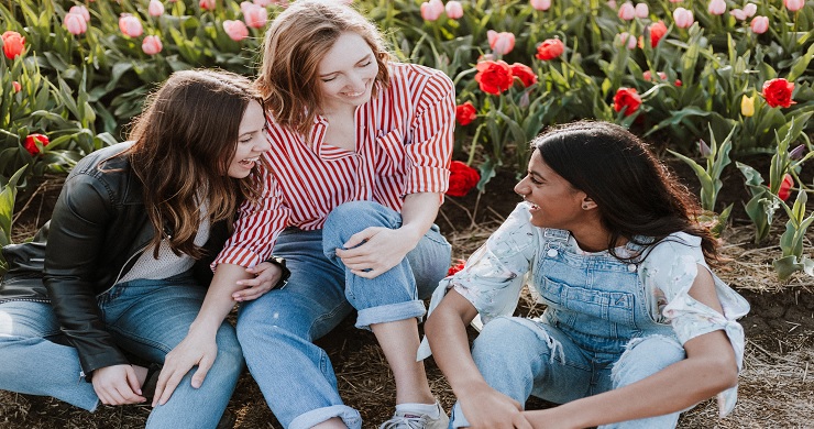 Photo of 3 young woman sharing a laugh in a field. Sharing is evangleism